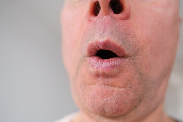 close-up and front view of mouth of an old caucasian man in his sixties, with strong wrinkles, bright emotions on his face, male skin care concept