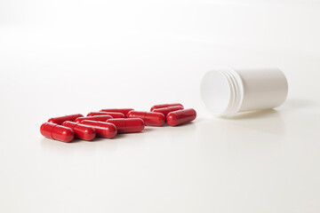 Red probiotics capsule and plastic bottle on white