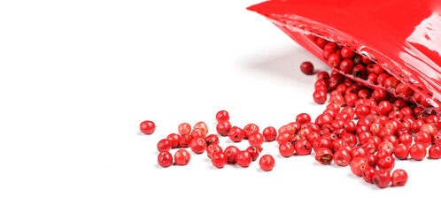 Pink peppercorns - dried fruits from peruvian peppertree ( Schinus molle ), with red plastic pack near, closeup detail from above