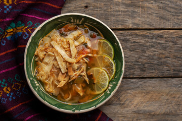 Mexican lime soup with chicken on wooden background