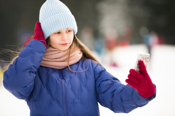 Adorable jeune fille prend des photos de selfie dans un magnifique parc d'hiver. Activités d'hiver...