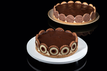 two Dutch pies topped with dark chocolate ganache over a reflective dark glass