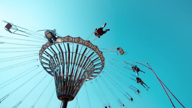 A rotating chair swing ride carousel with teenagers enjoying the ride in a parisian amusement park.