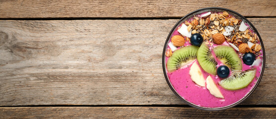 Obraz na płótnie Canvas Delicious acai smoothie with granola and fruits in dessert bowl on wooden table, top view. Space for text