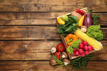 Different fresh vegetables on wooden table, flat lay. Space for text