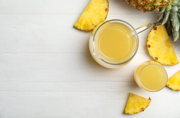 Delicious pineapple juice and fresh fruit on white wooden table, flat lay. Space for text
