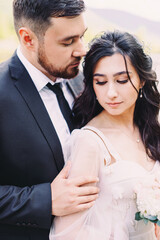 Portrait of the newlyweds on the background of nature. Summer wedding of beautiful bride and groom in stylish clothes