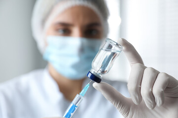 Doctor filling syringe with medication in clinic, focus on hand. Vaccination and immunization