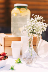 A table with a summer snack at a wedding celebration, sandwiches, lemonade, gypsophila sprigs in small vases