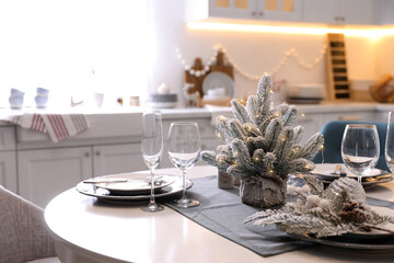 Table with set of dishware and beautiful Christmas decor in kitchen. Interior design
