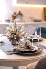 Table with set of dishware and beautiful Christmas decor in kitchen. Interior design