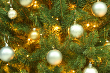 Obraz na płótnie Canvas Blurred view of glowing fairy lights and beautiful baubles on Christmas tree