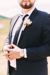 Stylish groom beard in black suit and boutonniere