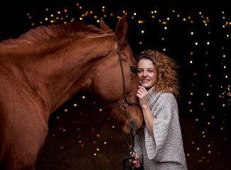 Beautiful curly girl with a red horse on a black background in New Year's decorations