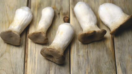 Fresh eringi mushrooms on a wooden surface.