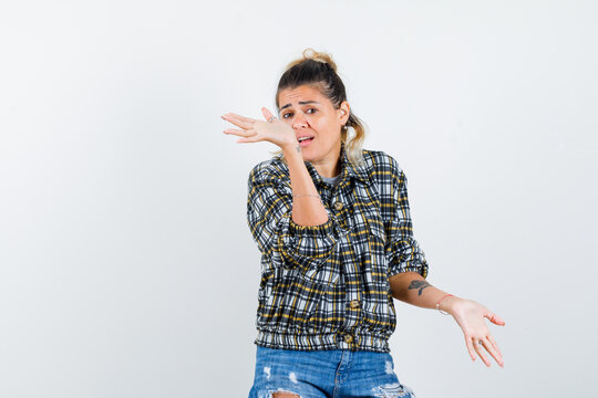  Young Lady Keeping Hands In Puzzled Gesture In Shirt,jeans And Looking Restless , Front View.