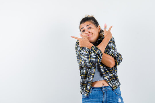  Young Lady Keeping Crossed Arms On Chest While Pointing Up In Shirt,jeans And Looking Hesitant , Front View.