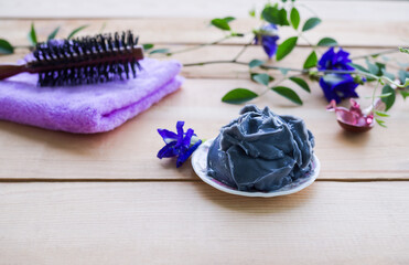 Anchan flower or butterfly Hair treatment on white plate with blur image of comb, towel on wood background. Spa aroma therapy hair concept.