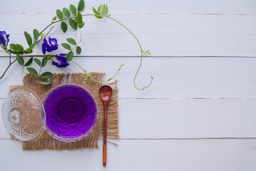 Anchan flower juice or blue pea flower herbal tea, butterfly pea in glass cup with wooden spoon on wood background. top view and copy space. herbal tea drink concept.