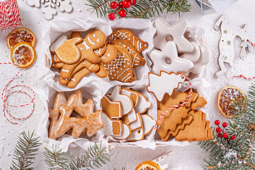 Top view of unpacked christmas present with sweets on a white textured surface framed by fir branches, close-up. Christmas celebration concept