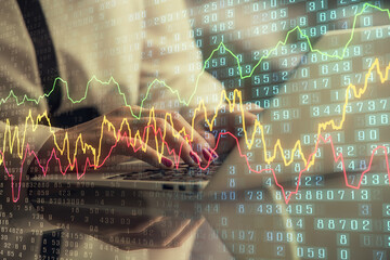 Double exposure of businesswoman hands typing on computer and financial graph hologram drawing....