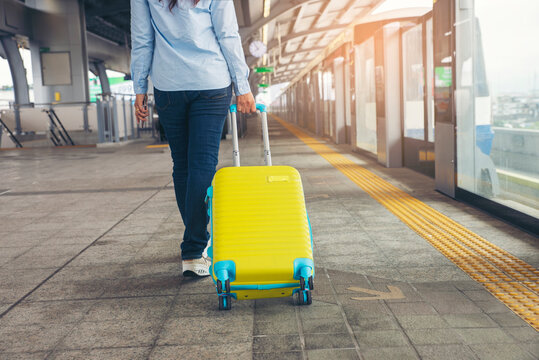 Travel concept. At Electric train station, Young Tourist Girl walking and Dragging luggage suitcase bag and searching hotel at platform. Asian women waiting for transit train and planning happy holida