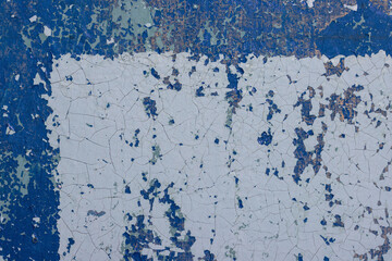 Blue peeling paint on the wall. Old concrete wall with cracked flaking paint. Weathered rough painted surface with patterns of cracks and peeling. High resolution texture for background and design.