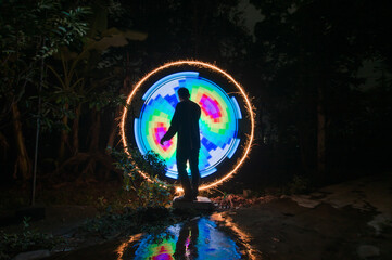 One person standing alone against creative color circle light painting as the backdrop	