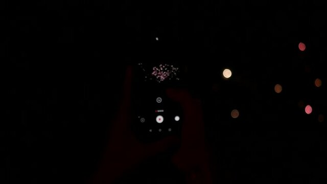 New Year celebration, a person is filming the fireworks on the phone
