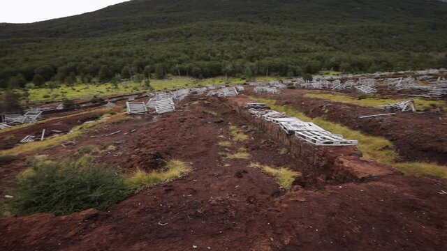 Environmental damage. View of an abandoned industry of natural peat bog exploitation. The red peat field of moss Sphagnum magellanicum, forest and Andes mountains in Ushuaia, Patagonia Argentina. 