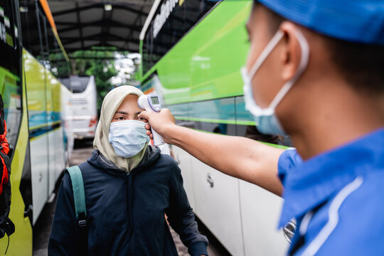 asian passenger temprature check using thermogun before riding bus