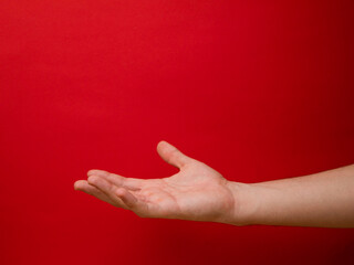 Female hand shows gesture on a red background.