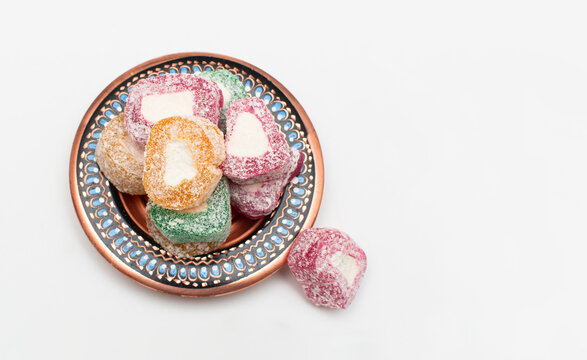 Colorful Turkish delight (aka lokum) in traditional bowl isolated on white background. Middle Eastern dessert popular in the month of Ramadan. 