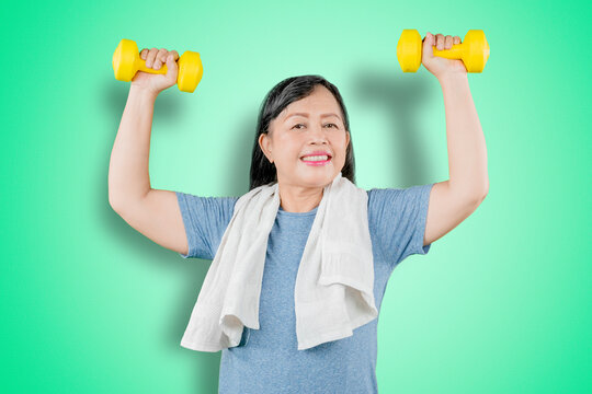 Happy Old Woman Lifting Two Dumbbells On Studio