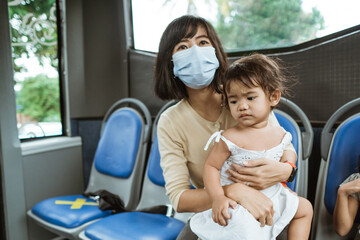 mother and daughter riding public transport during pandemic wearing facemask