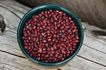 overhead view of ceramic bowl with red aduki beans and natural wooden background