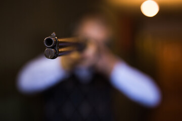 Closeup of muzzle of single barrelled shotgun on blurred background of aiming man
