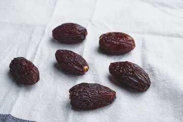 fruit date palm on a white tablecloth and craft paper. symbol of abundance in Ramadan. sweet berries from a tree. several sweet dried berries. raw food