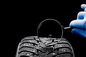 huge nail on a tyre over black background. studio shot. copy space. repair car tire concept....