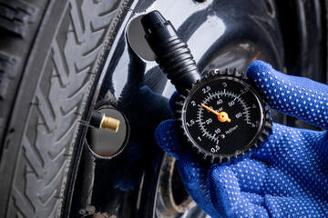 man measuring tyre air pressure by using pressure gauge. car service concept. studio shot