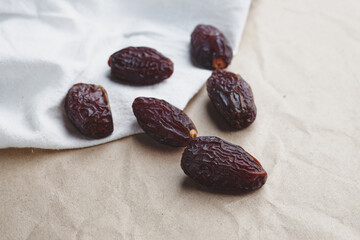 fruit date palm on a white tablecloth and craft paper. symbol of abundance in Ramadan. sweet berries from a tree. several sweet dried berries. raw food