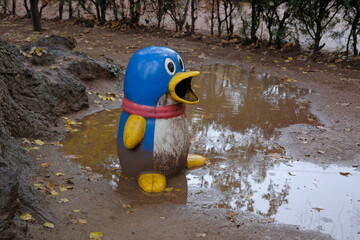rain in an abandoned park. dirty and unkempt penguin in an old abandoned city park