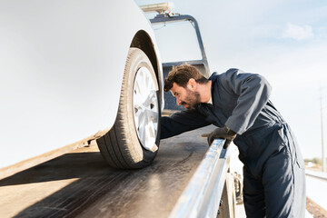 Tow truck worker securing the car on the platform