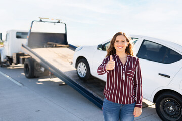 Portrait of a happy young woman doing an approval sign for the tow truck service