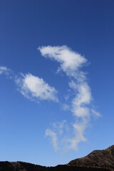 山の上の青空に、龍が上るような雲がある風景