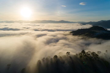 Aerial view Drone shot of Beautiful scenery landscape sunlight in the morning sunrise above flowing fog waves on mountain peak tropical rainforest in phang nga thailand