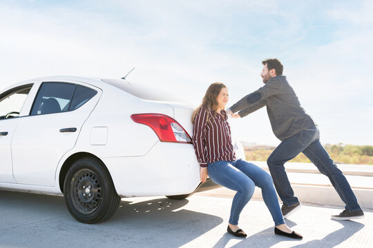 Couple struggling to push their broken-down car on the highway