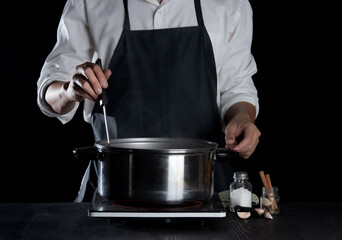 Man cooking soup in pot on dark background,Cooking at home
