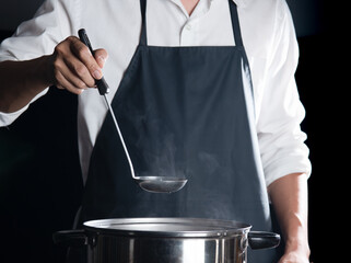 Man cooking soup in pot on dark background,Cooking at home
