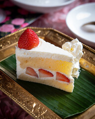 Portion of sliced cake with cream and strawberries